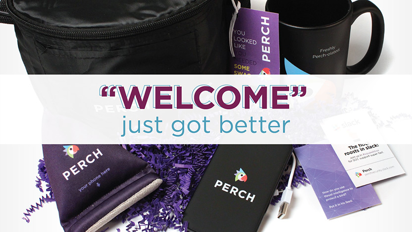 A welcome gift set including a black mug with "Freshly Perched Coffee," a black pouch, a phone stand, a pen, and a card with "WELCOME just got better" text. The items are surrounded by purple shredded paper.