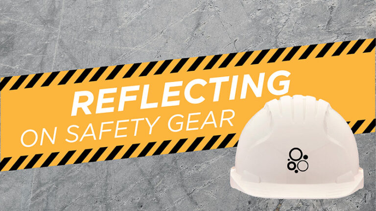 A white hard hat with a black logo is placed in front of a yellow and black striped background. The text reads "Reflecting on Safety Gear" against a textured gray backdrop.