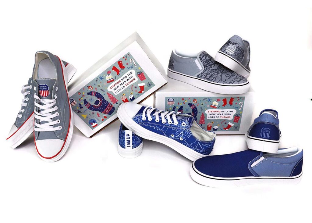 A variety of sneakers are displayed with a decorative shoe box and a shoe cleaner. The sneakers feature graphic designs in shades of blue, gray, and white. A box reads "Stepping into the Art of Making.